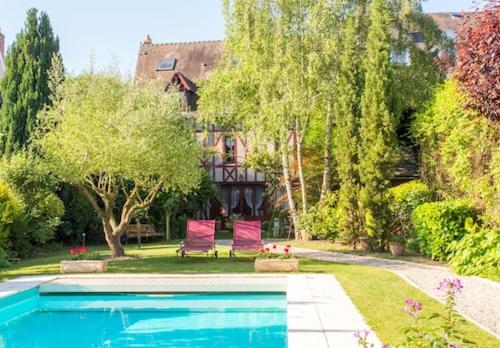 a swimming pool in a yard with two chairs at Hôtel Spa - Au Charme Rabelaisien in Amboise