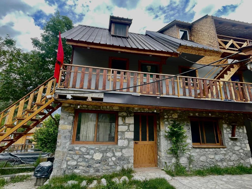 a house with a deck on the side of it at Shpia e Mikut Guesthouse in Theth