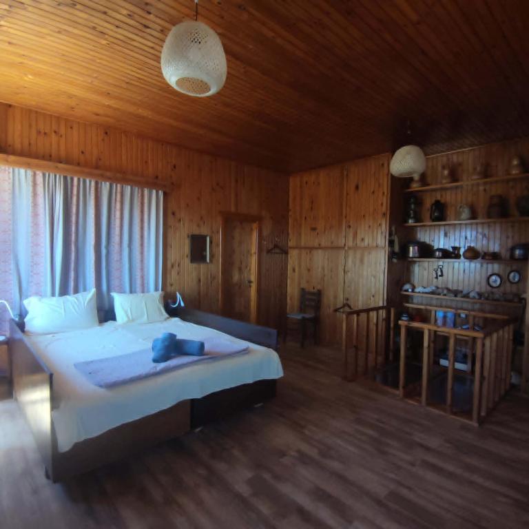 a bedroom with a large bed and a wooden ceiling at Rising Sun Guesthouse in Mesokhória