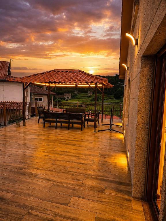 a deck with benches and a sunset in the background at A Veiga Grande in Pontevedra