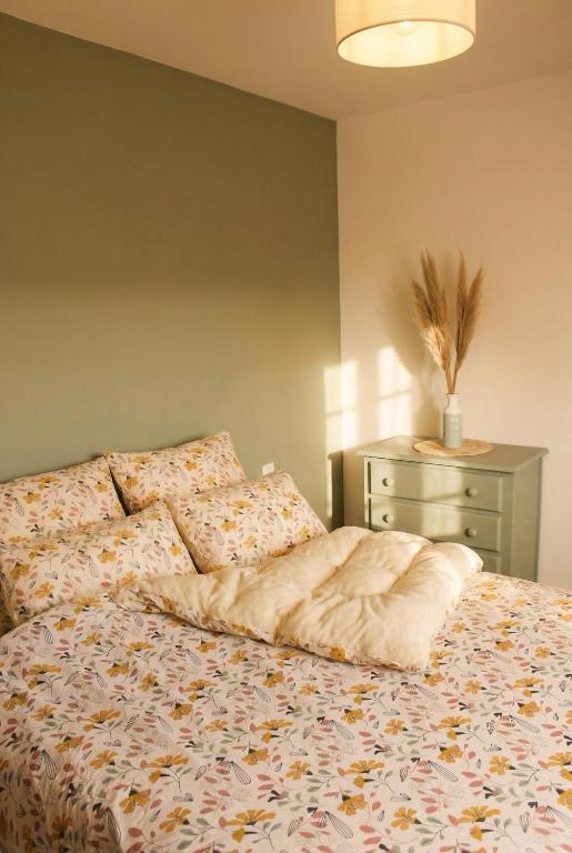 a bed with a comforter and a dresser in a bedroom at Escapade au Mont St Michel in Pleine-Fougères