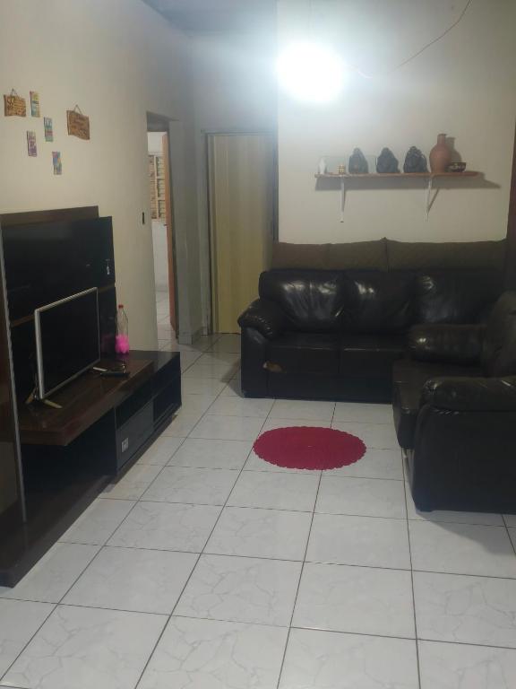 a living room with a black leather couch and a television at Hostel Pachamama in Presidente Prudente