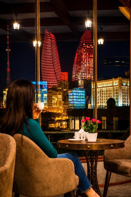 a woman sitting at a table with a view of the city at Sultanahmet Hotel in Baku
