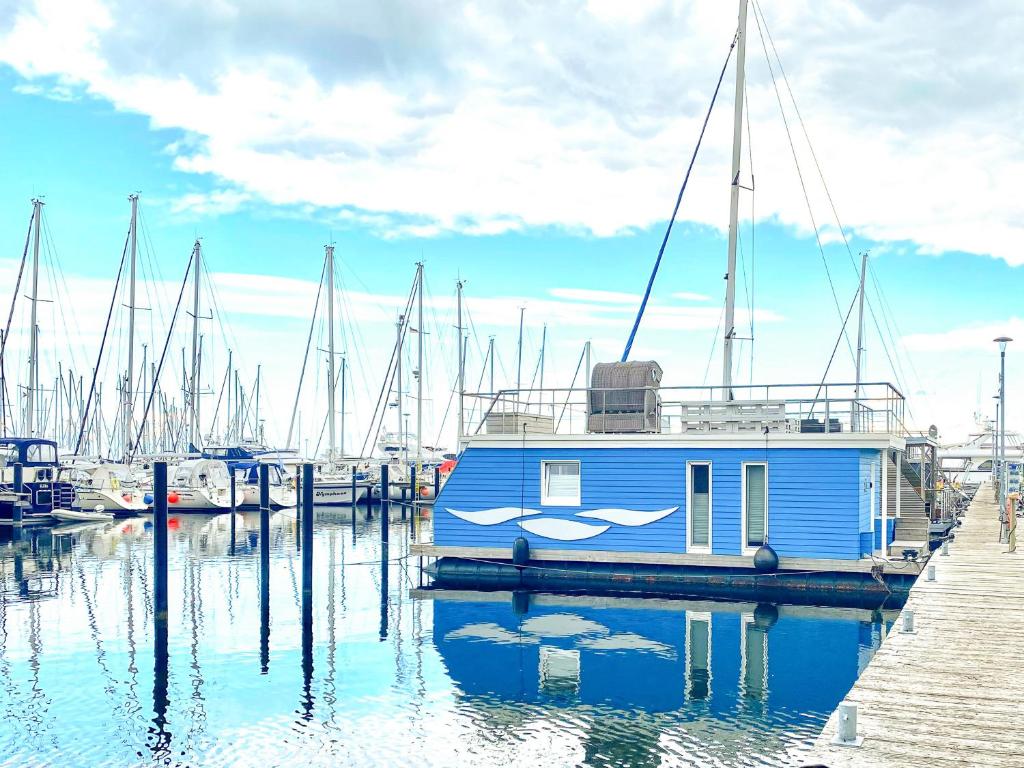 a blue boat is docked at a dock at Hausboot Yara am Steg 1D in Heiligenhafen