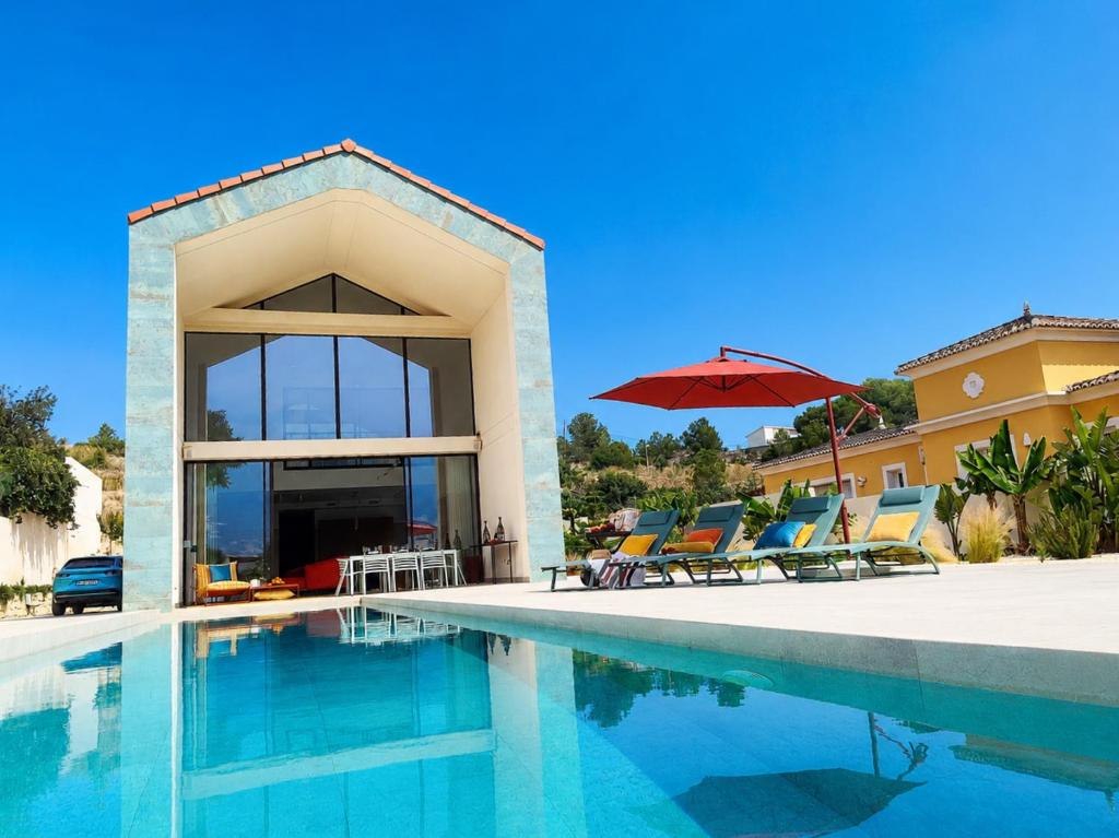 a swimming pool with chairs and a red umbrella at Luxury Villa Galaxy Beach 12min walk 15m pool in Calpe