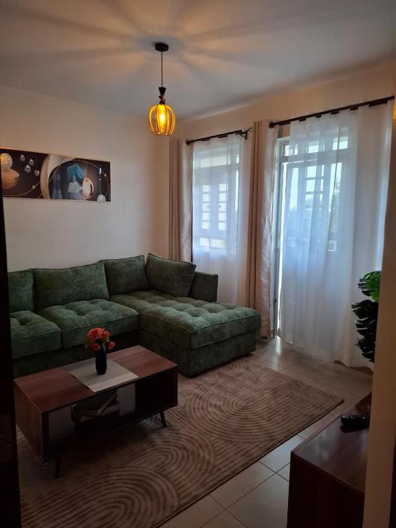 a living room with a green couch and a coffee table at Serene 63 Luxe in Murangʼa