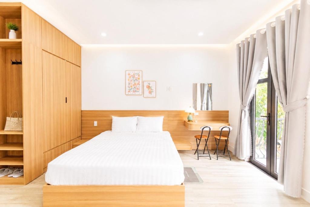 a bedroom with a white bed and a large window at Fame Apartment in Dong Hoi