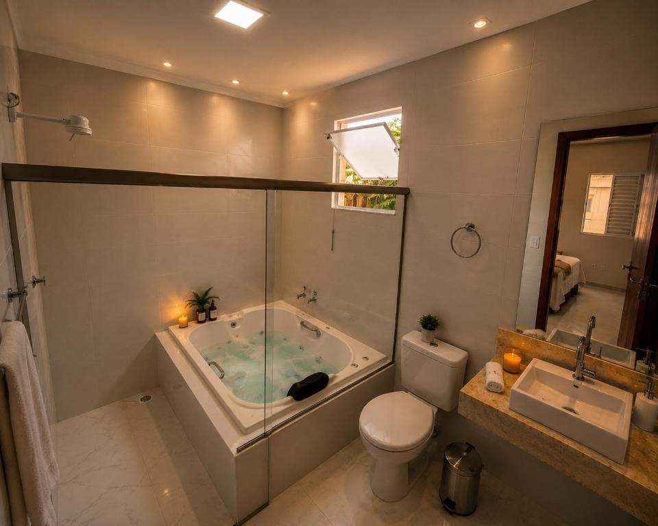 a bathroom with a tub and a toilet and a sink at Suíte com Jacuzzi Vista de Escarpas 3 in Capitólio