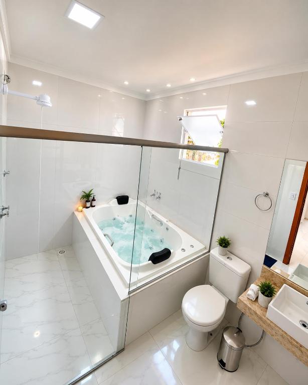 a bathroom with a tub with a toilet and a sink at Suíte com Jacuzzi Vista de Escarpas 4 in Capitólio