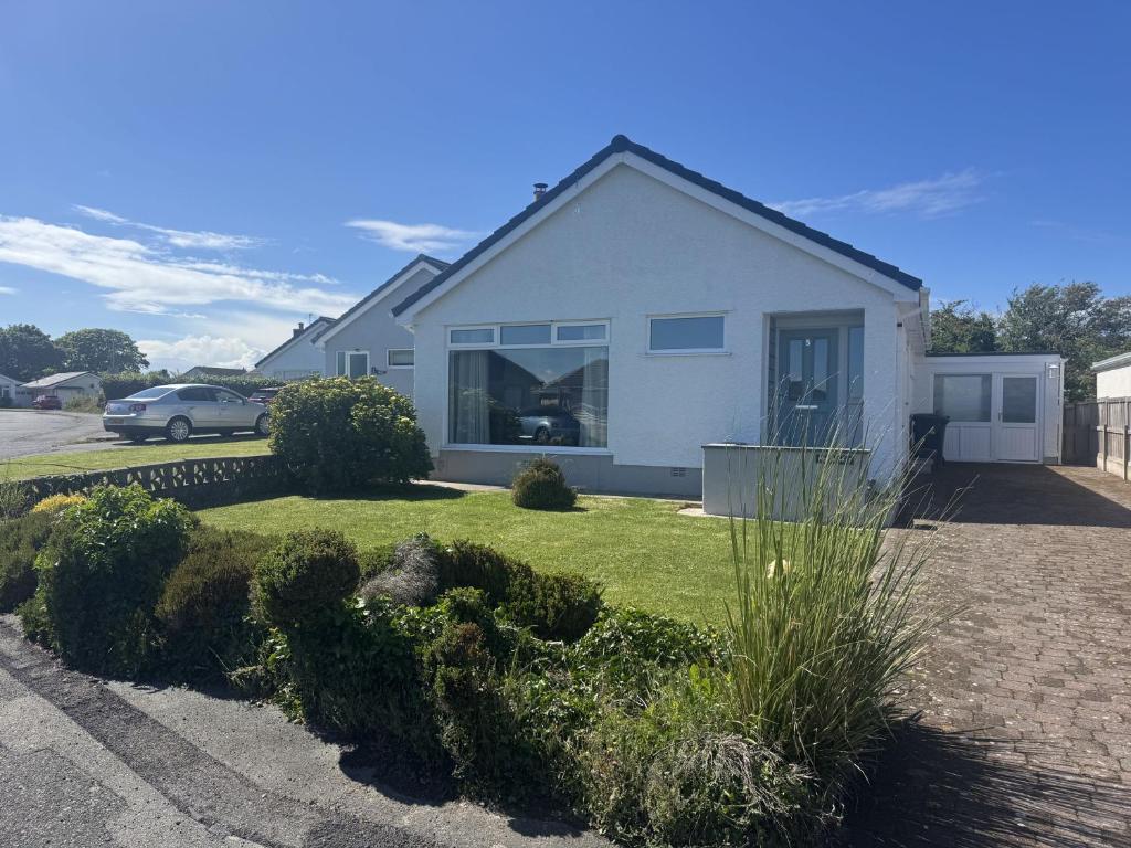 a white house with a car parked in a driveway at Mor Annedd Cymyran in Valley