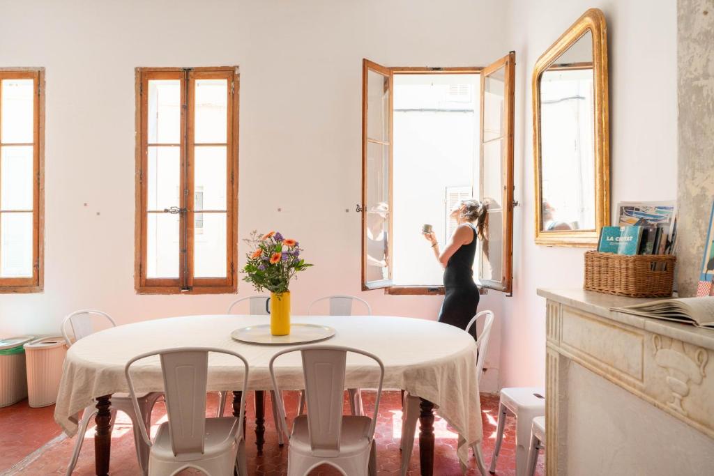 a woman standing in a kitchen looking out the window at Joli Cocon - Meublé de tourisme classé 2 étoiles - Terrasse - Parking in La Ciotat