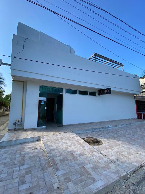 a white building with a sign on top of it at Hotel Nella Mar in Puerto Colombia