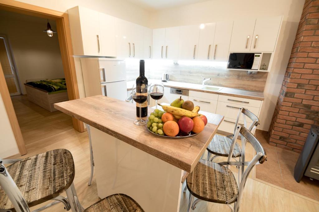 a kitchen with a bowl of fruit and a bottle of wine at Apartmán Mary in Štôla