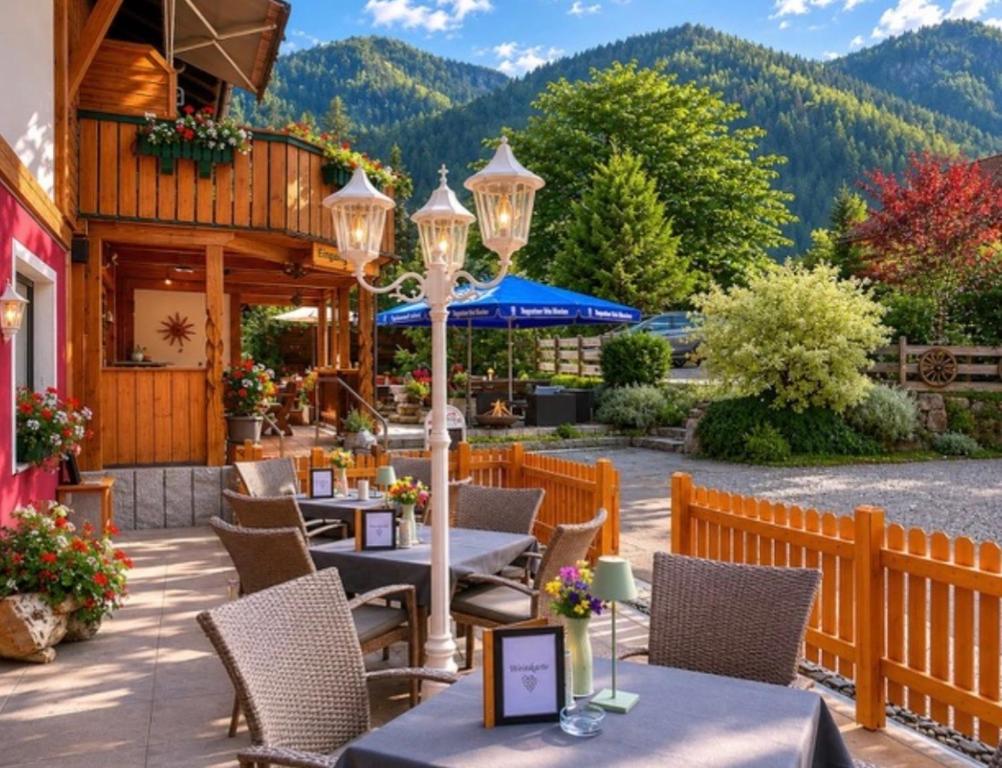 a patio with tables and chairs with mountains in the background at Pension Bergheim in Tannheim