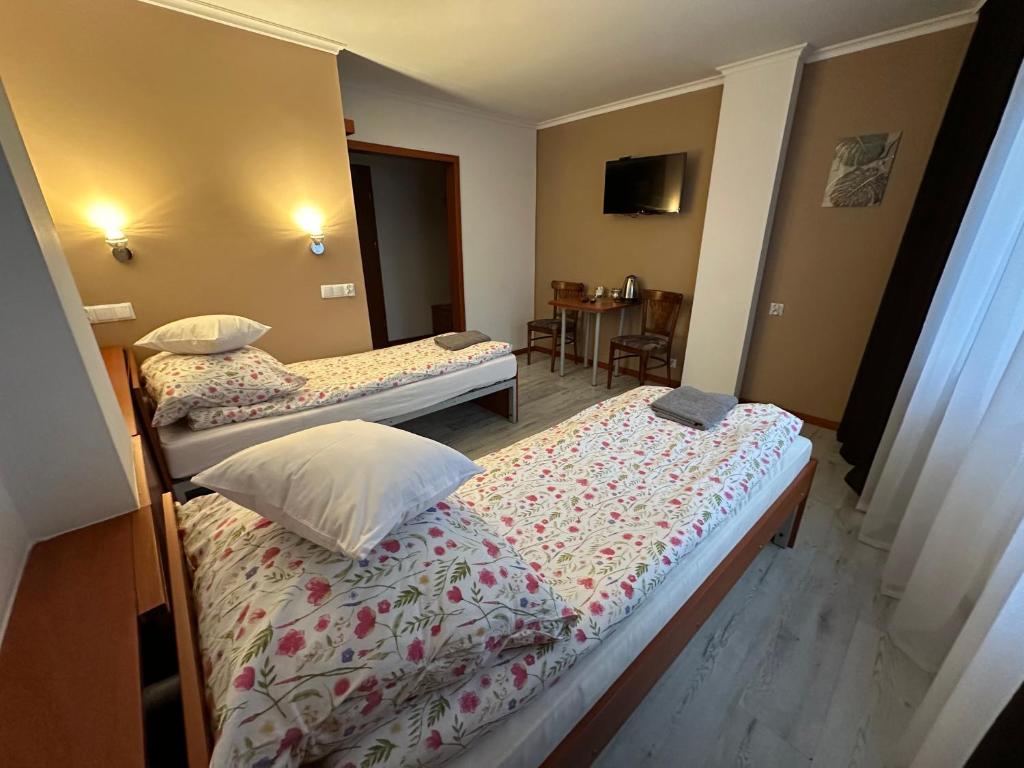 a hotel room with two beds and a table at Bianco - pokoje noclegowe in Częstochowa