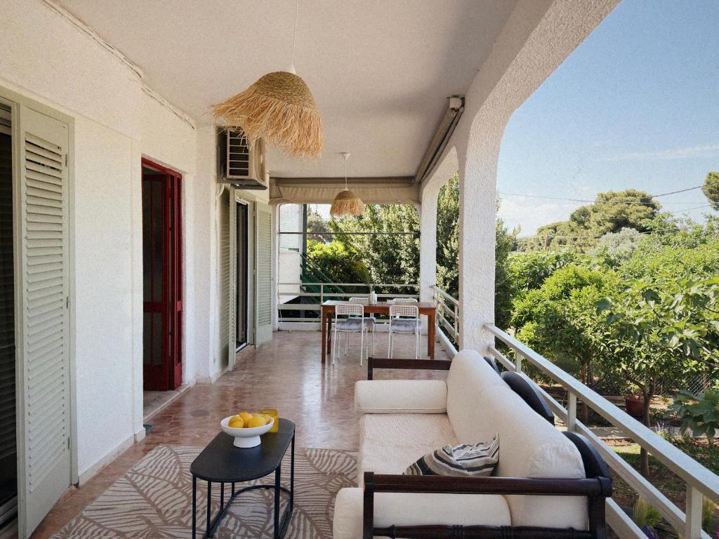 a porch with a white couch and a table at Sun Garden House Athens in Nea Makri