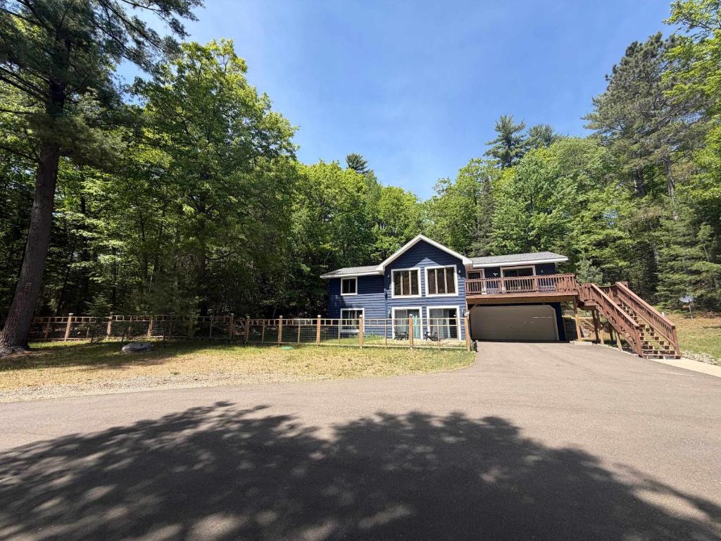 a blue house with a bridge over a driveway at Big St Germain Hideaway in Sayner