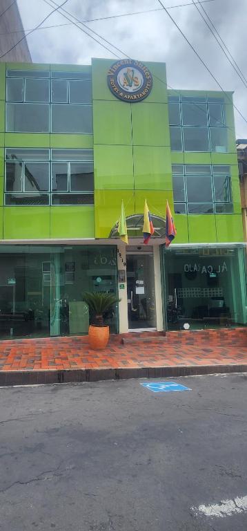 a green building with umbrellas in front of it at Vincent Suites Hotel in Pasto