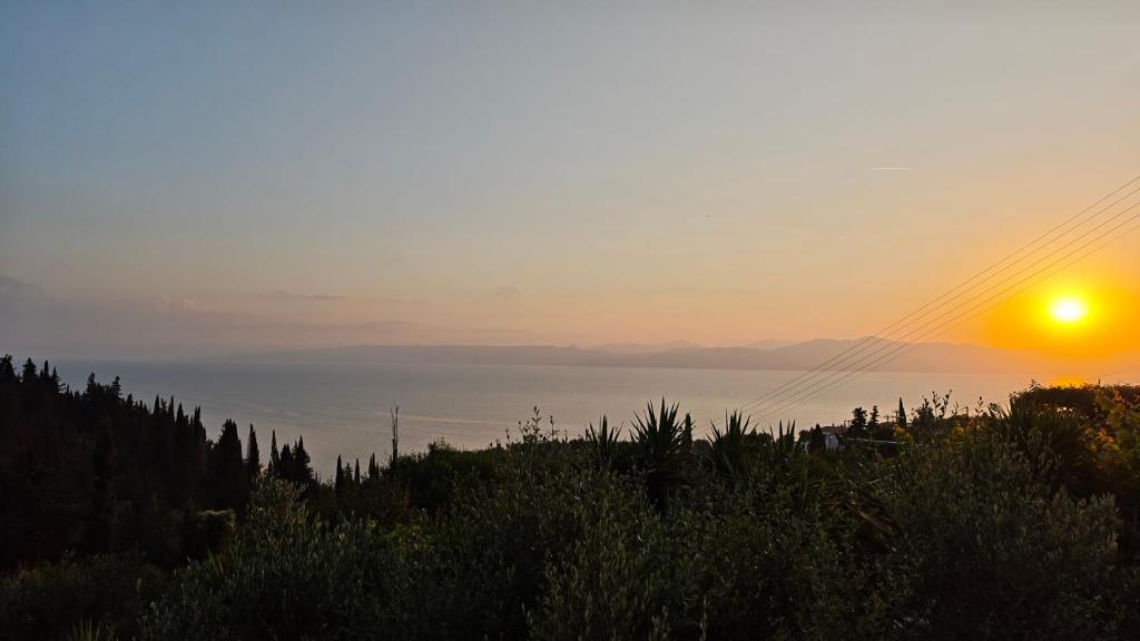 a sunset over the water with the sun in the sky at Liokorni Village in Gaios