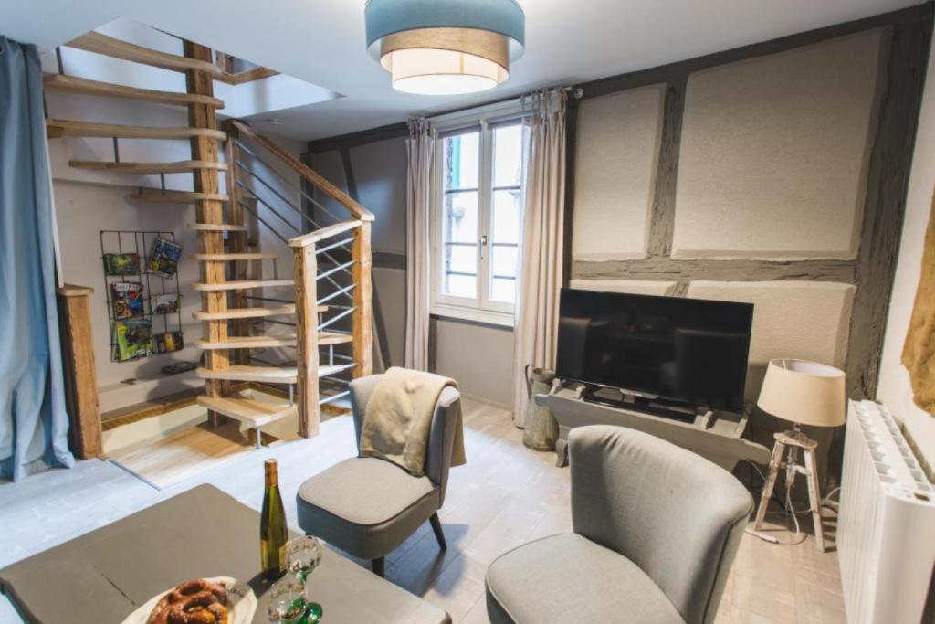 a living room with a couch and a television and a staircase at Le Cottage Bleu- In the Heart of Riquewihr by La Maison Bleue in Riquewihr