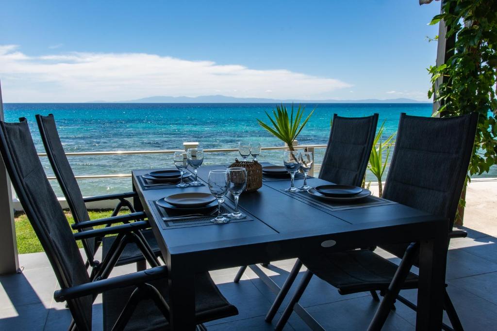 a table with wine glasses on a balcony with the ocean at Sunset Shores Mola Kaliva in Mola Kalyva