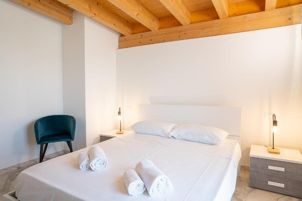 a white bedroom with a bed and a chair at Venti del Garda in Montinelle