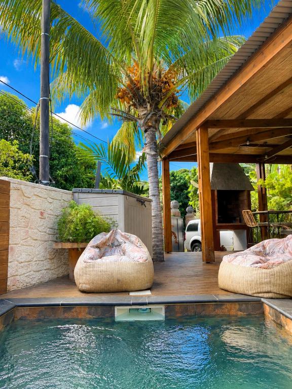 a swimming pool with two ottoman chairs next to a house at Lodge Sakayu - Charme, calme & piscine privée in Saint-Louis