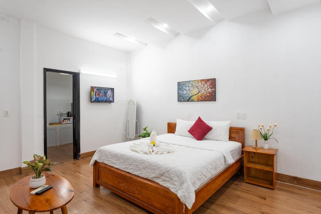 a bedroom with a bed with white sheets and red pillows at Chic Studio Homestay in Hue