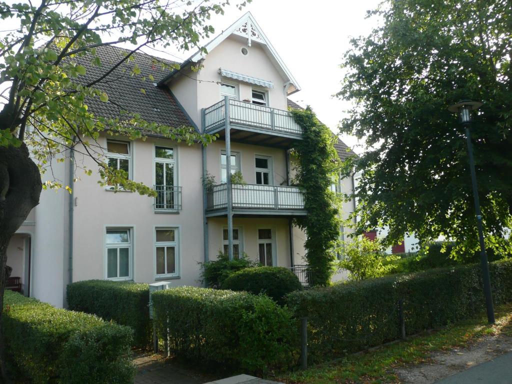 a white house with a balcony on top of it at Ferienwohnung Am Molli Nr. 2 in Kühlungsborn