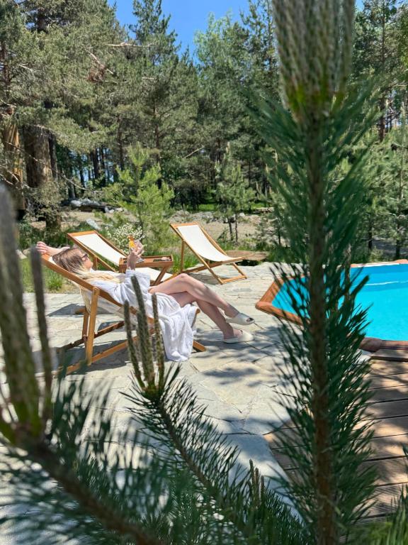 a woman sitting in lawn chairs on the beach at Maglian Forest Retreat in Divčibare