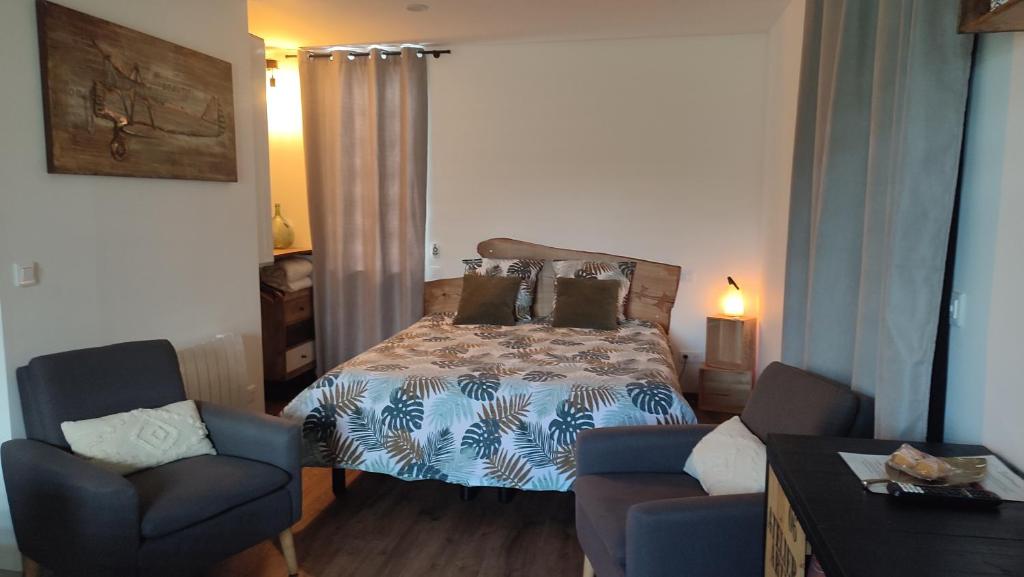 a bedroom with a bed and two chairs at Studio Cozy, Vallée de la Saulx in Trémont-sur-Saulx