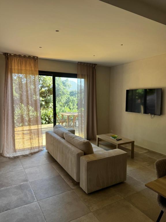 a living room with a couch and a large window at Rez-de-villa 65m2 climatisé in Propriano