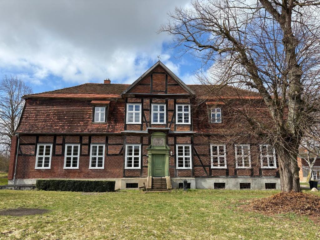 a large red brick building with a green door at Altes Gutshaus Schwiessel in Prebberede