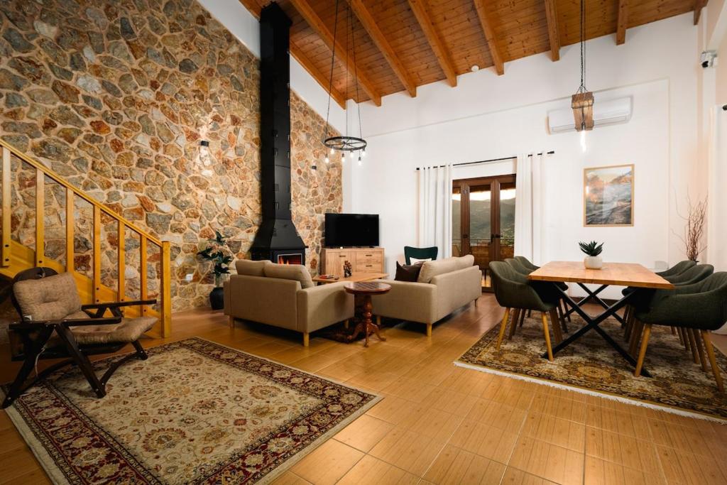 a living room with a stone wall and a table and chairs at Epi tis Stigos in Kalavrita
