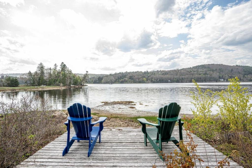 two chairs sitting on a dock near a lake at Oceanfront House Steps to Water in French Village