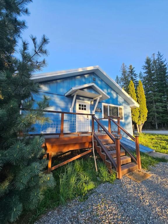 a blue tiny house with a porch and a tree at Lil Blue Dog Haven in Sagle
