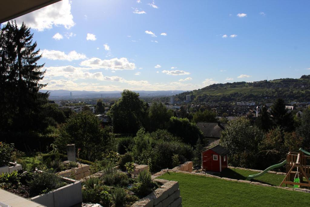 a view of a garden with a red house in the distance at Dreiländerblick in Lörrach