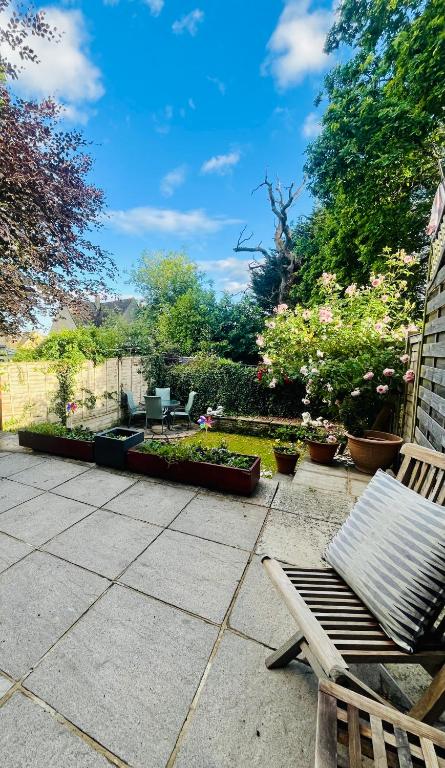 a patio with two chairs and a garden with flowers at Hideaway Cottage in Bourton on the Water