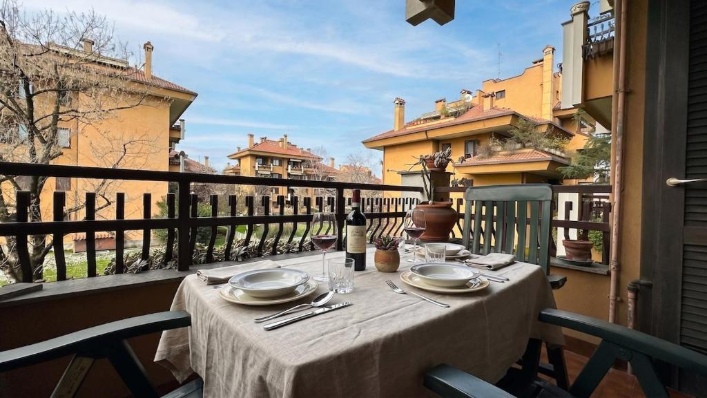 a table with plates and wine glasses on a balcony at [10 minuti dall'aeroporto] Linate Studio Flat in Peschiera Borromeo