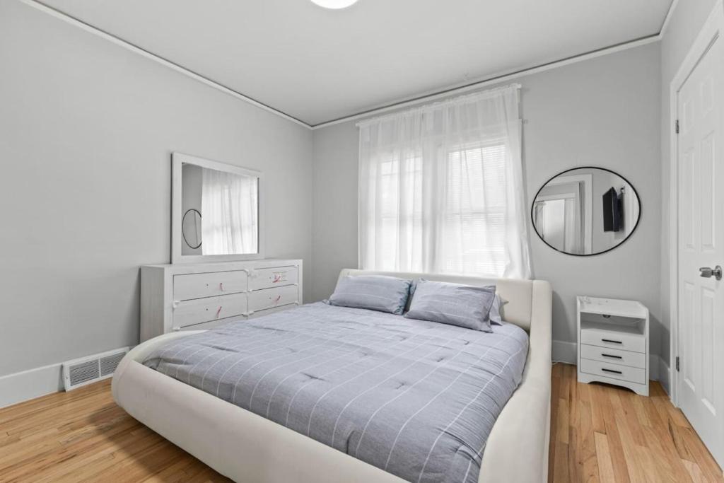 a white bedroom with a bed and a mirror at 2 BR - Fully Equipped Dearborn Home in Dearborn