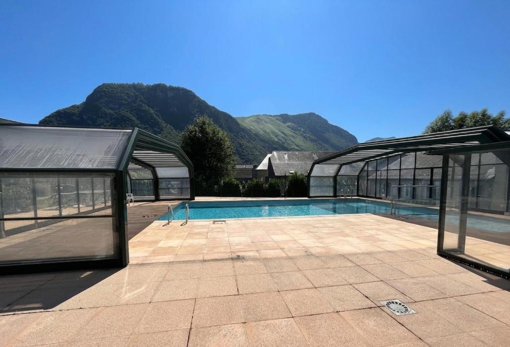 a swimming pool in a greenhouse with mountains in the background at Appartement Le Refuge du Vautour in Bielle