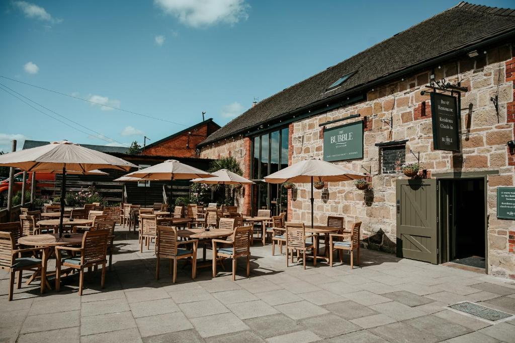 an outdoor patio with tables and chairs and umbrellas at The Bubble at Stenson in Stanton