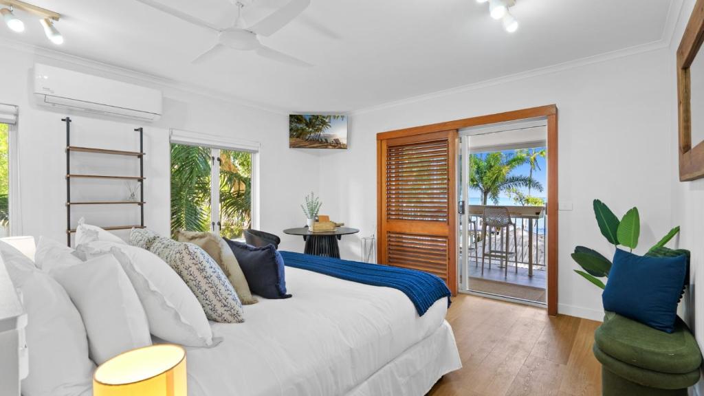 a bedroom with a white bed and a balcony at Absolute Beachfront Studio with Pool and Ocean Views in Palm Cove