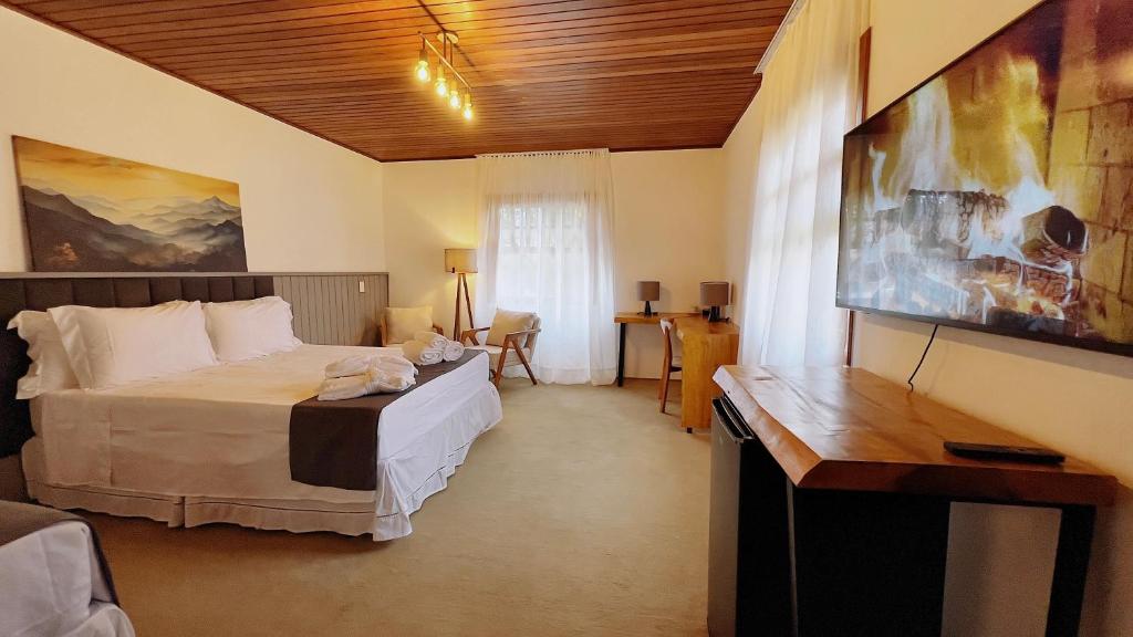 a bedroom with a bed and a desk in it at Casa Capivari Boutique in Campos do Jordão