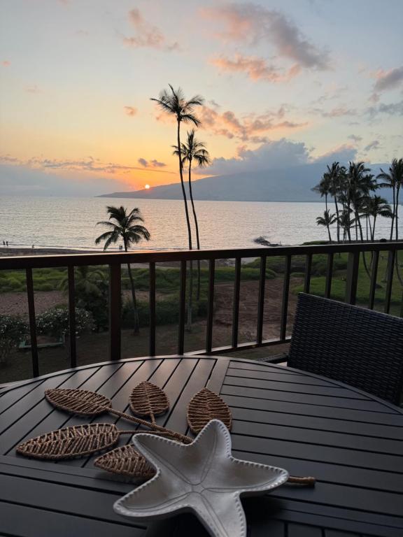 a table with two starfish on a balcony with the ocean at Oceanfront Artist Condo Panoramic Maui Sunsets in Kihei