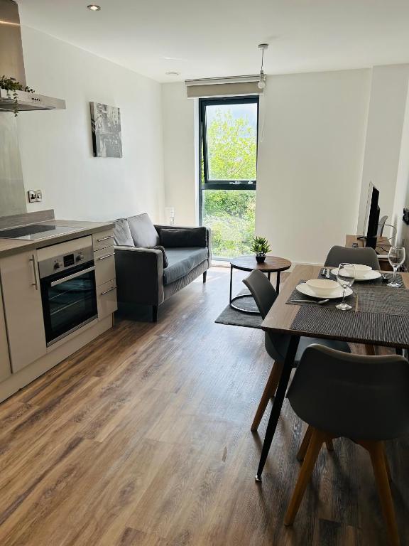 a kitchen and living room with a table and a couch at Near Old Trafford & Media City 2BR Flat in Manchester