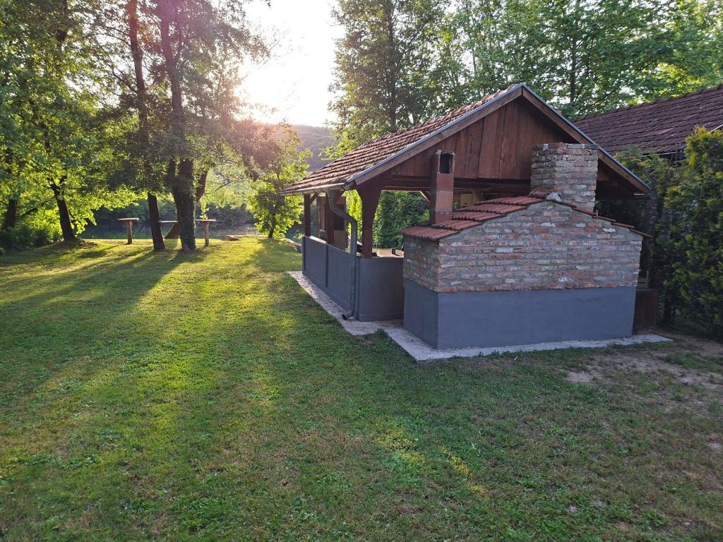 a small building in a field with trees and grass at Plaža STEFIN KUTAK in Rudice