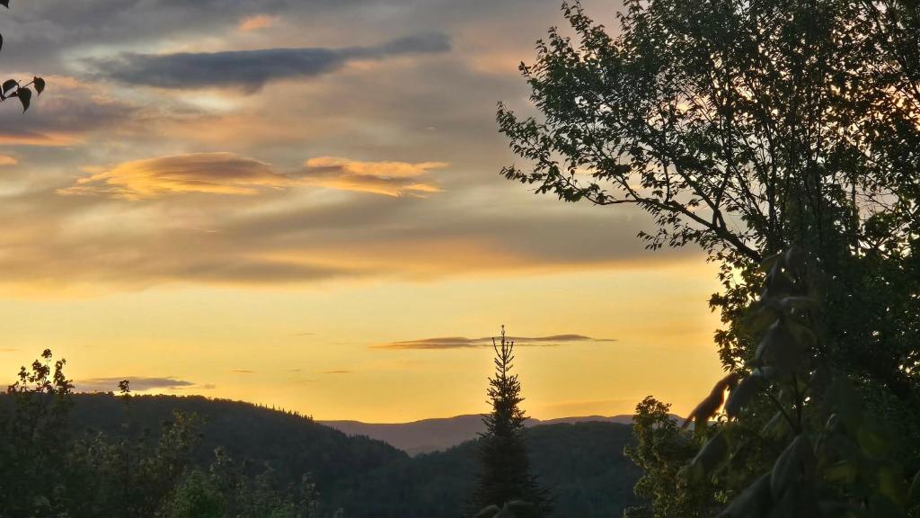 a sunset in the mountains with a cross in the sky at La Romane Heated Pool, Hot Tub, Billiards & Fire in Val-David