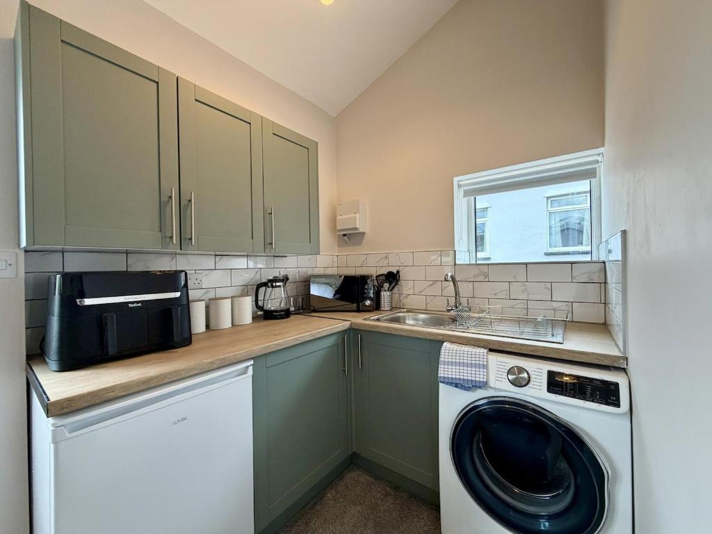 a kitchen with a washing machine and a sink at The Den- Cosy Studio in Dowlais
