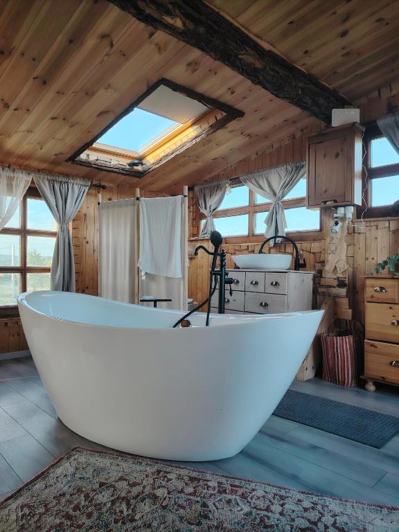 a large white bath tub in a room with wooden ceilings at Lombfészek in Rezi